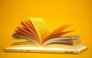 Een geopend boek ligt op een tablet tegen een gele achtergrond.