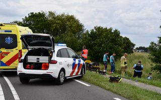 Een politieauto en een ambulance bij een fietspad. Hulpverleners staan in het gras.