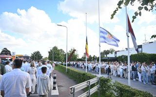 Mensen lopen in witte kleding in een stoet