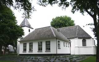 Buitenkant kerkgebouw met torenspits. Kerk is wit van kleur.