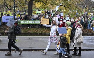 Een groep mensen staat met spandoeken en tekstbordjes te protesteren voor de mogelijkheid tot abortus en tegen de Mars voor het Leven. Op de voorgrond lopen deelnemers aan die mars voorbij.