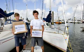 Twee jongens met elk een doos waarop de naam Wereldschool staat.