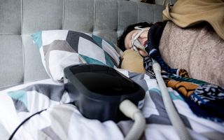 Een vrouw slaapt met behulp van een slaapapneu-apparaat van zorgtechnologieconcern Philips. beeld ANP, Rob Engelaar