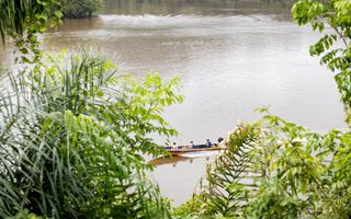 Boomstamboot vaart over de brede rivier.