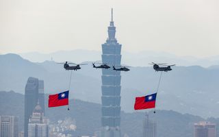 Twee vlaggen van Taiwan hangen onder Taiwanese Chinookhelikopters tijdens de inauguratie van president William Lai op 17 mei in de hoofdstad Taipei. Op de achtergrond is het hoogste gebouw van het eiland zichtbaar: de 508 meter hoge Taipei 101. beeld EPA, Ritchi B. Tongo
