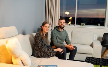 Twee jonge mensen zitten op een witte bank en glimlachen.