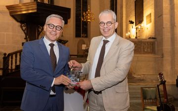 Man met bril, stoppelbaardje, bij een microfoon.