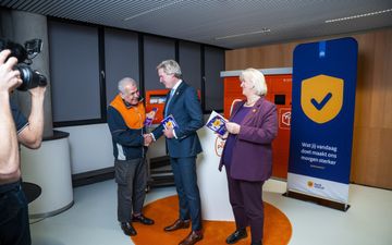 Drie mensen lachen en schudden elkaar de hand. 