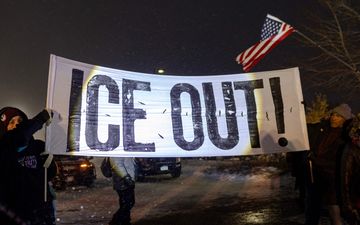 Mensen houden een spandoek met de woorden ”Ice Out!” omhoog.