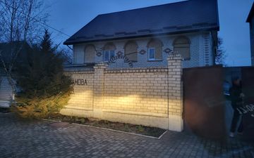 Stenen kerkgebouw met puntdak en muur ervoor.