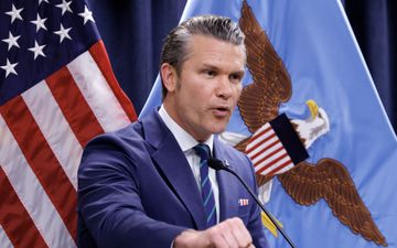 Man in blauw kostuum voor twee vlaggen, de vlag van de Verenigde Staten en die van Iran