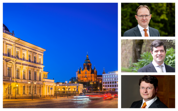 Historische gevels worden bij schemering verlicht, met op de achtergrond de iconische torenspitsen. Rode achterlichten van auto’s zijn zichtbaar.