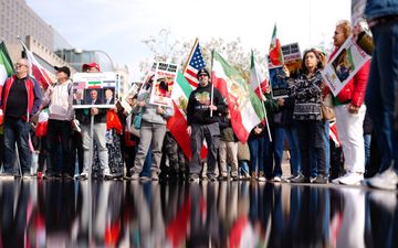 Mensen houden Iraanse en Amerikaanse vlaggen vast.