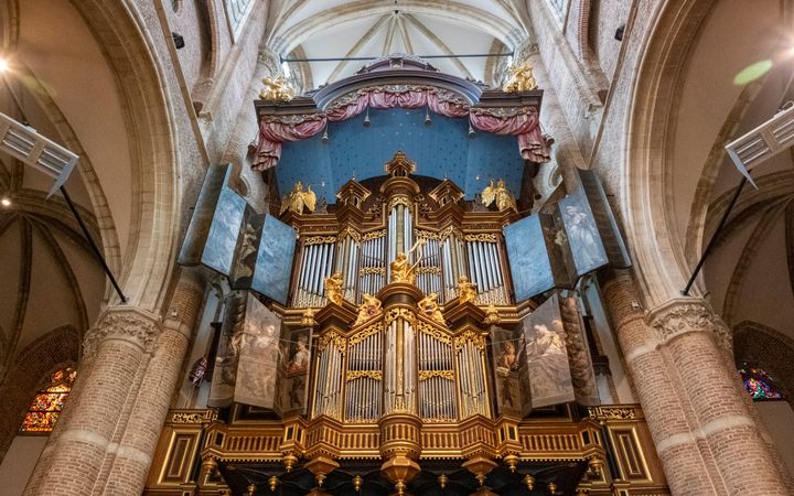Een oud orgelfront heeft aan beide kanten beschilderde orgelluiken en hangt in de oude kerk.