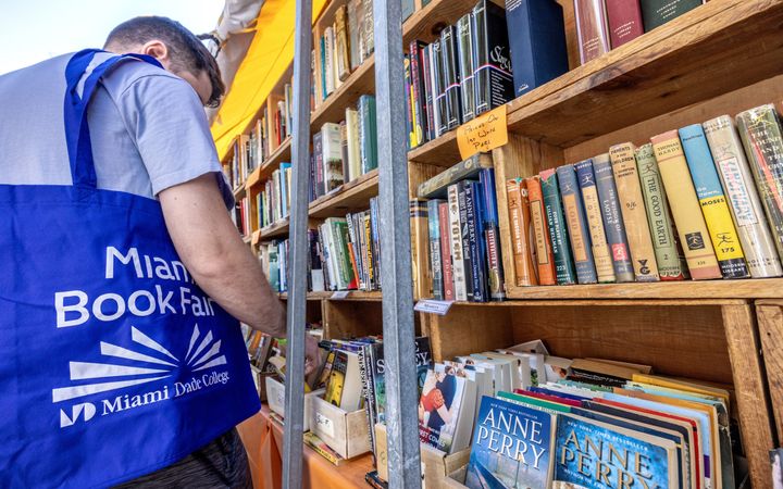 Algemene foto van een jongen bij een kast met Engelstalige boeken erin.