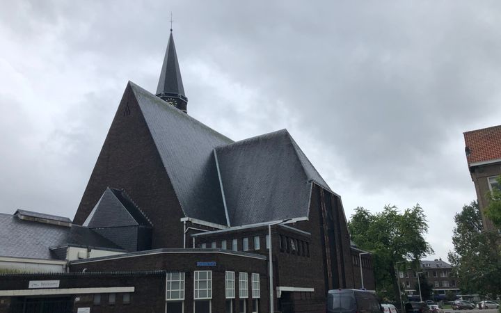Historisch kerkgebouw met op de voorgrond geparkeerde auto’s.