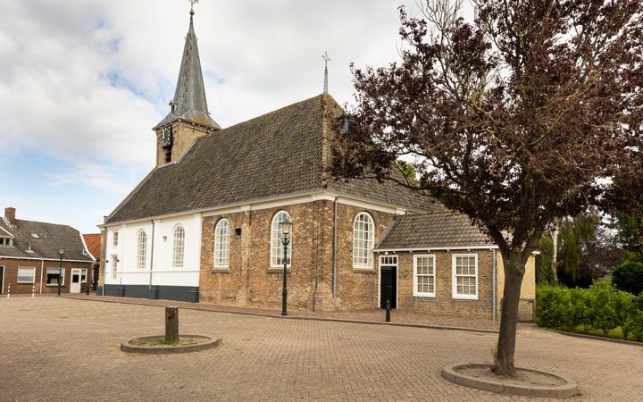 Oud, bakstenen kerkgebouw met torenspits.