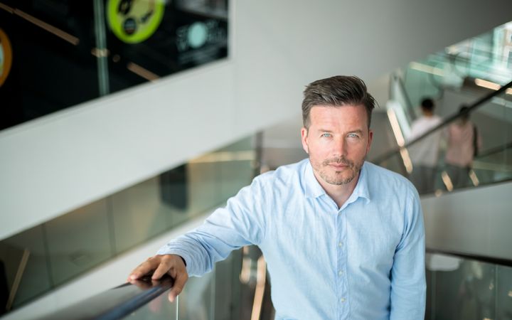 Man in blauw overhemd, bruin haar en licht baardje.