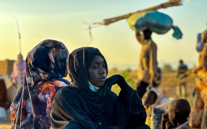Vrouw in zwarte jurk kijkt treurig in de verte. 