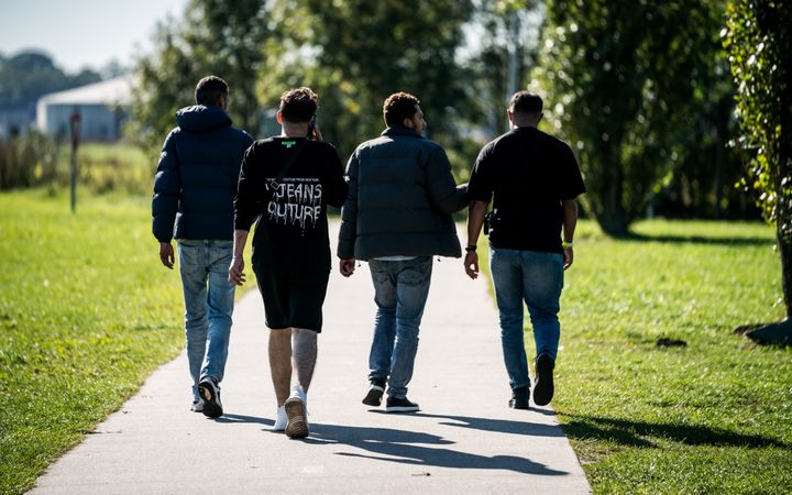 Vier mannen met buitenlands uiterlijk lopen op een weggetje.