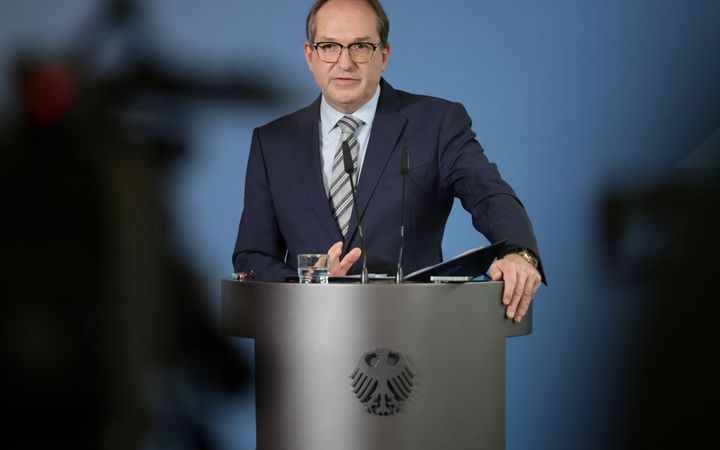 Een man in pak spreekt vanachter een katheder 