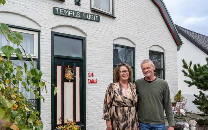Man en vrouw oor een witgeverfd huis met naambordje ”Tanis” en gevelnaam Tempus fugit . 
