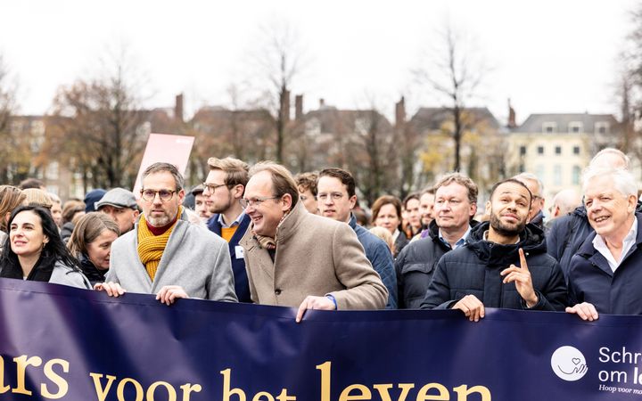 Een groep mensen loopt achter een metersbreed spandoek van de stichting Schreeuw om Leven 