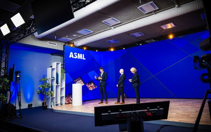 Drie mannen in donkere pakken op een groot podium