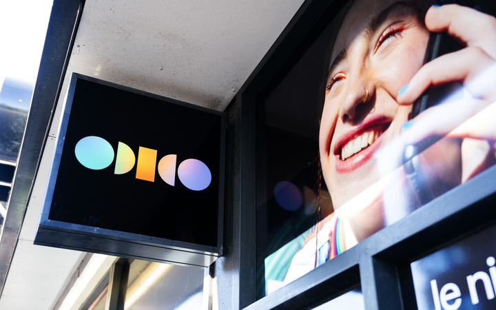Een uithangbord met het logo van Odido hangt aan de gevel van een winkel.