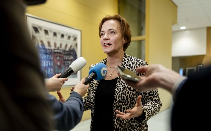 vrouw in tijgerprintjasje door microfoons omringd