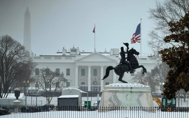 Standbeeld van een ruiter te paard staat voor een wit gebouw. 