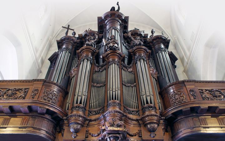 Een rijk gedecoreerd donker houten orgelfront met onder andere beelden van musicerende engelen. 