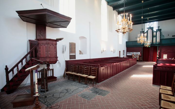 Het interieur van een oude hervormde kerk, met preekstoel, kerkbanken, kroonluchters en orgel.