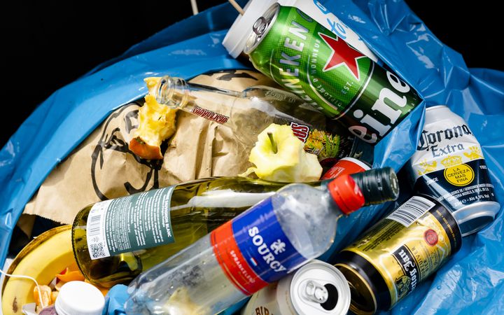 Kleurige blikjes en ander afval in een blauwe zak