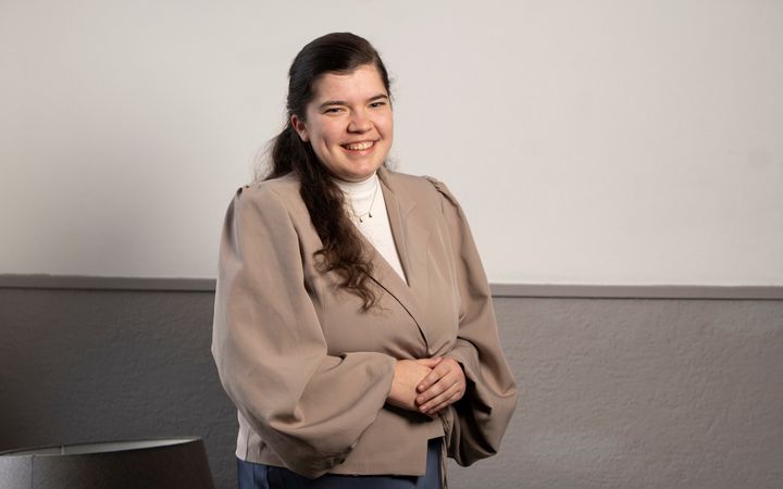 Een jonge vrouw met donker haar kijkt lachend in de camera.