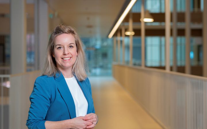 Vrouw met blond haar in blauw jasje. 