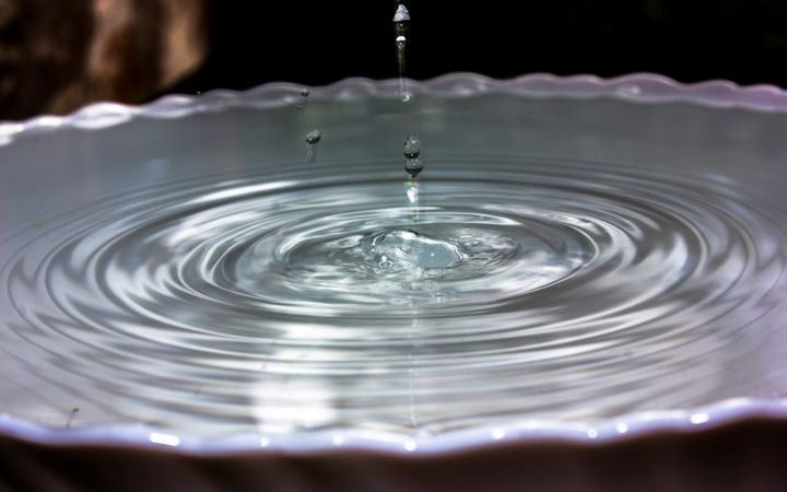 Waterdruppels vallen in een schaal gevuld met water.