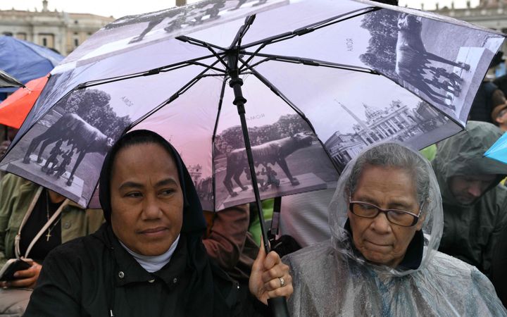 Twee vrouwen onder een paraplu, met daarop onder meer een afbeelding van de Sint-Pieterskerk.