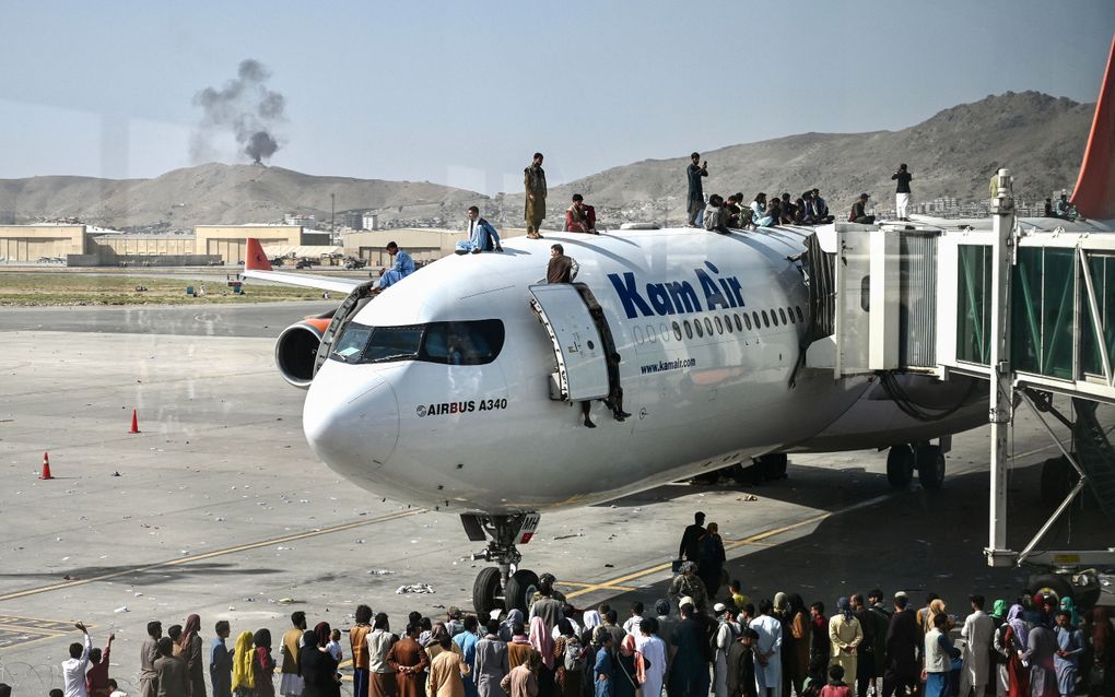 Afghanen proberen weg te komen via het vliegveld van Kabul, maandag. beeld AFP, Wakil Koshar