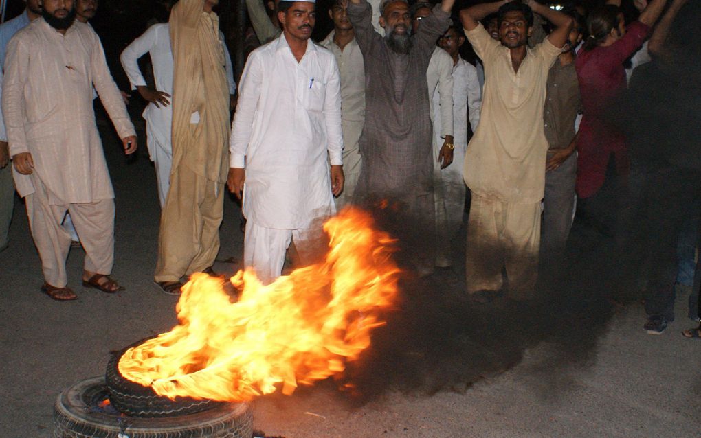 Politie probeert een brandende autoband in Lahore te doven. Foto EPA