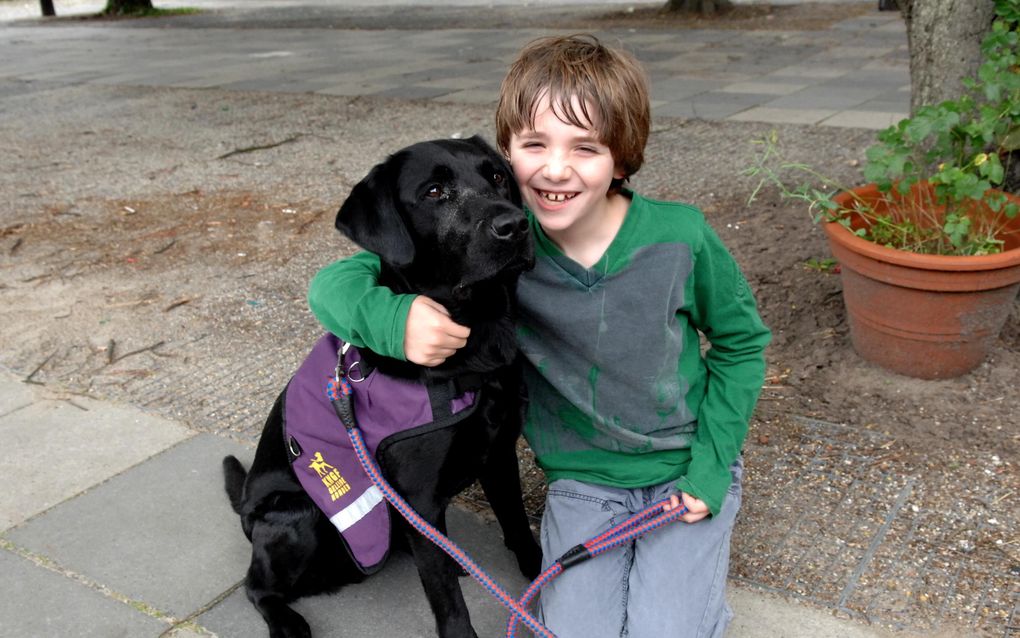 Dobbs is een prima maatje voor Robbert Brummel (8), die zegt dat hij graag met zijn autismegeleidehond knuffelt en speelt. „Als je iets heel spannend vindt, gaat Dobbs mee”, vult zijn moeder aan. Foto Jos van Leeuwen