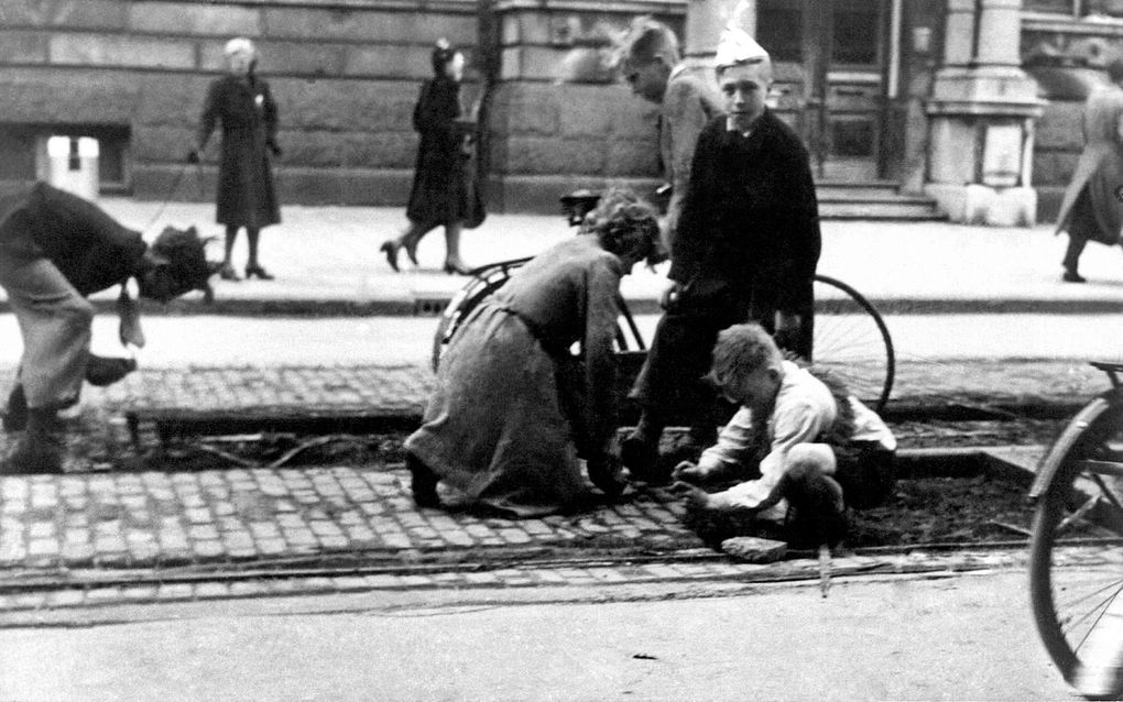 Beeld uit de Hongerwinter van 1944-1945 in Amsterdam: om de kachel te kunnen stoken worden de houten blokjes tussen de tramrails weggesloopt. Foto ANP