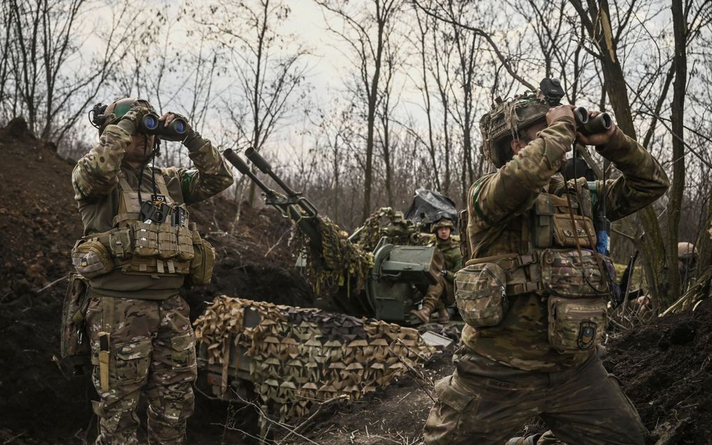 Oekraïense militairen observeren met verrekijkers Russische posities in Bachmoet. Oekraïne houdt al negen maanden stand in de zwaar verwoeste stad. beeld AFP, Aris Messinis