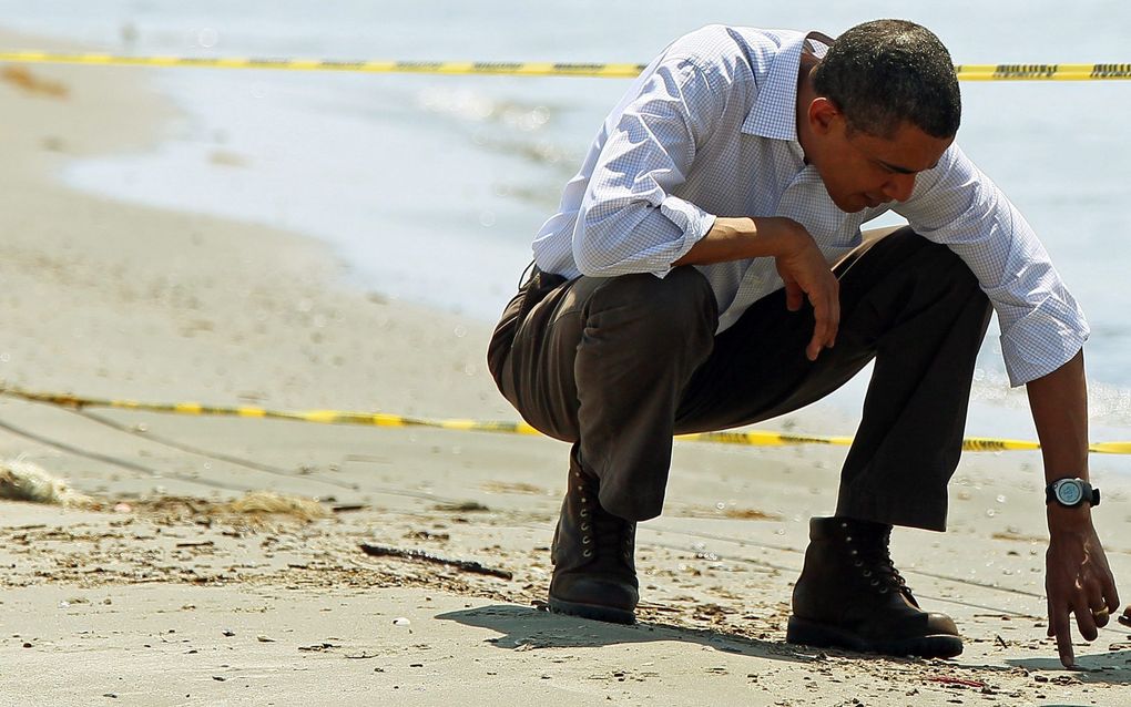 PORT FOURCHON - President Barack Obama, pakt een prop teer op tijdens zijn wandeling over het strand van van Port Fourchon in de Amerikaanse staat Louisiana. Foto EPA