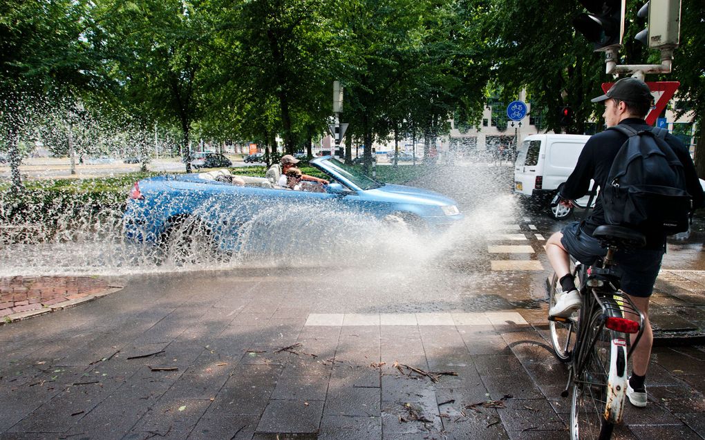 Extremer weer lijkt ook in Nederland vaker voor te komen. Vorige week beëindigde noodweer met zware windstoten en stevige plensbuien een periode met tropische temperaturen. Foto: kinderen rennen door een onder water gelopen straat in Kaatsheuvel. Foto ANP