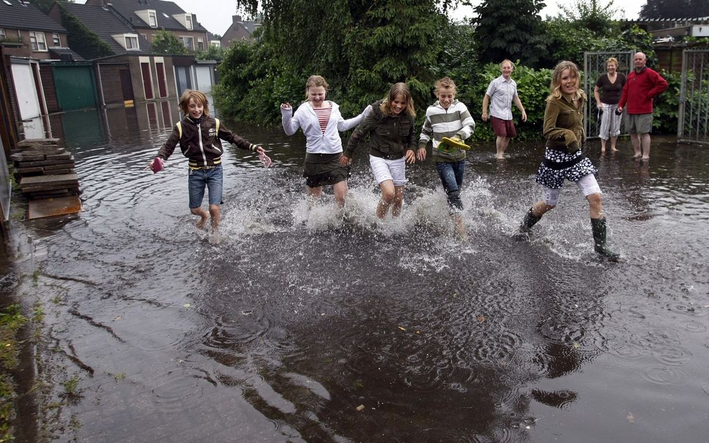 Extremer weer lijkt ook in Nederland vaker voor te komen. Vorige week beëindigde noodweer met zware windstoten en stevige plensbuien een periode met tropische temperaturen. Foto: kinderen rennen door een onder water gelopen straat in Kaatsheuvel. Foto ANP