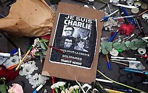 Een poster met de tekst ”Je suis Charlie" tussen symbolische pennen en potloden op de Place de la Republique in Parijs. beeld EPA