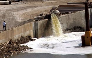 METAIRIE â€“ Een pomp in de Amerikaanse stad Metairie spuit onafgebroken water in een afvoerkanaal, terwijl achter de inmiddels gedichte dijk rondom de stad het waterpeil zakt en er steeds meer aan de oppervlakte komt. Foto EPA