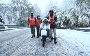 Mensen slepen een scooter voort door de eerste sneeuw in Srinagar, de zomerhoofdstad van Jammu en Kasjmir. beeld AFP