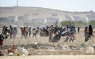 Koerdische vluchtelingen uit Syrië steken de grens met Turkije over. beeld AFP